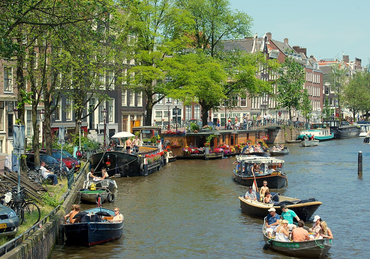Bicycles on a small bridge over a quiet Jordaan canal lined with gabled houses