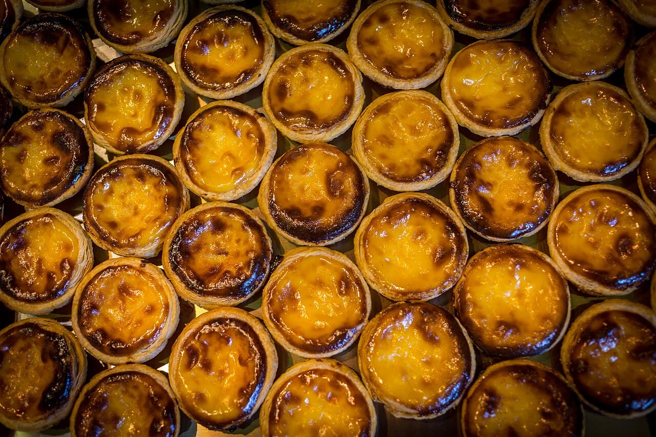 Warm pastéis de nata dusted with cinnamon on a café plate