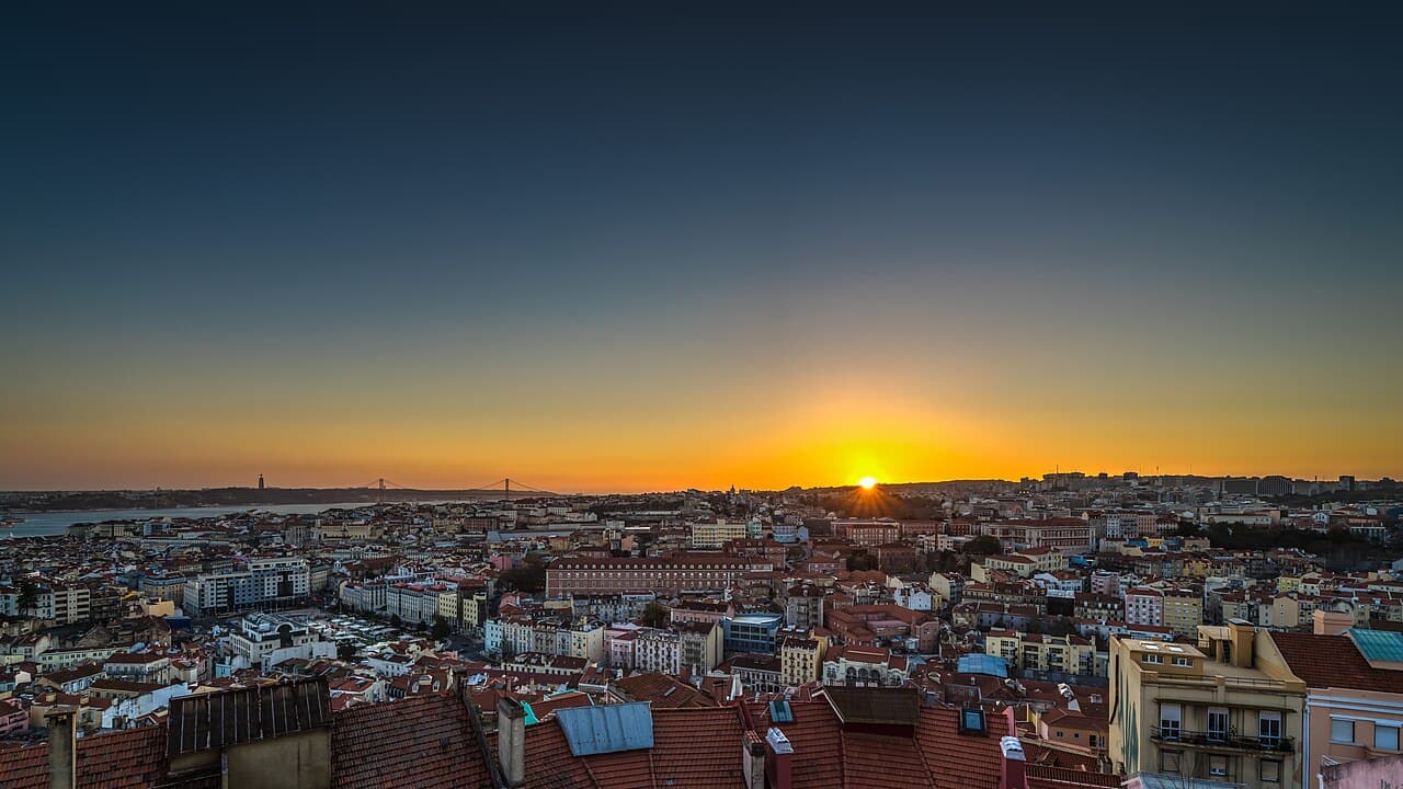 Crowd watching sunset over Lisbon's castle and river from Senhora do Monte viewpoint
