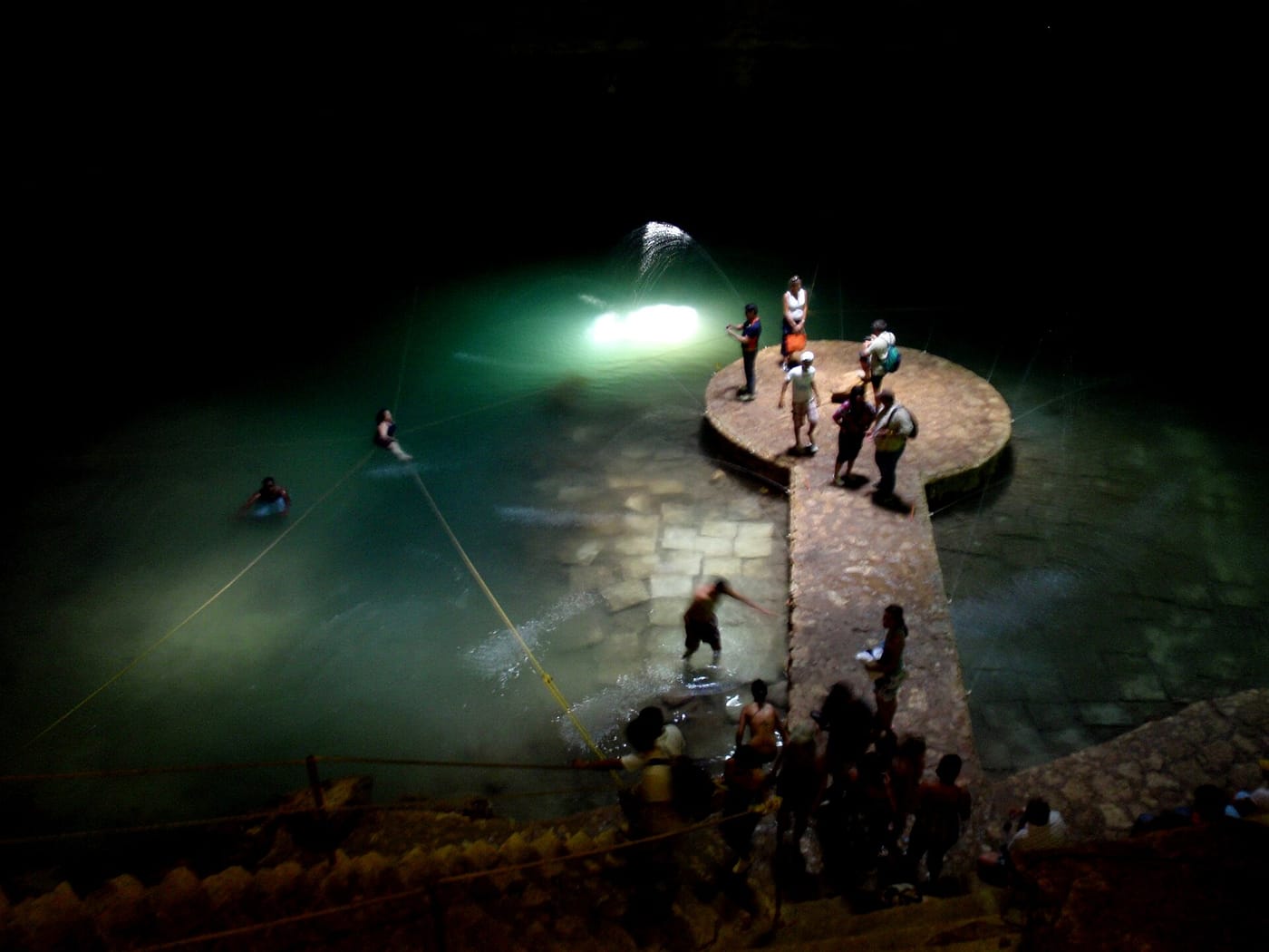 A shaft of light hitting the stone platform in the round cavern of Cenote Suytún