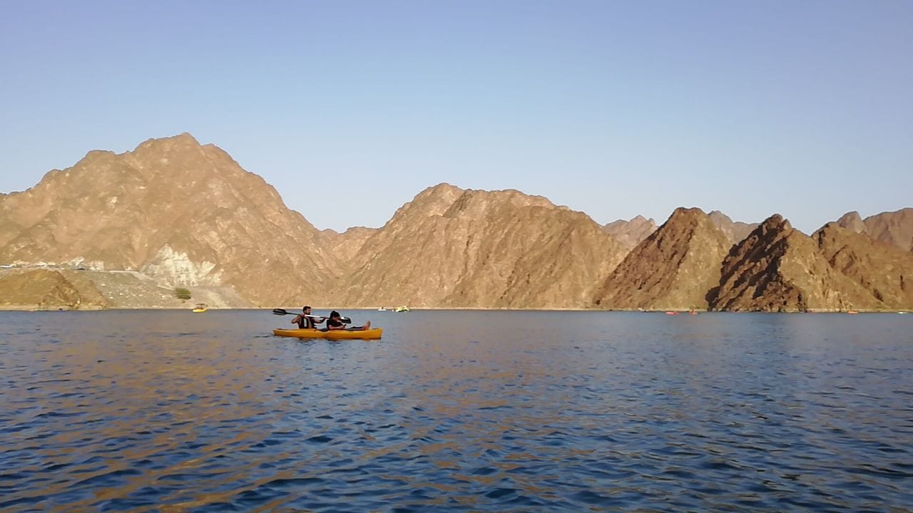 Kayakers on the turquoise Hatta Dam among the mountains near Dubai