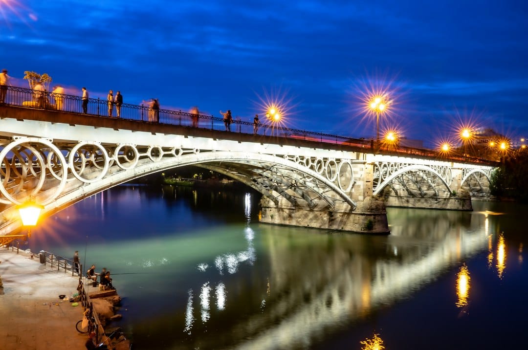 The Triana Bridge lit up over the Guadalquivir river in Seville at dusk